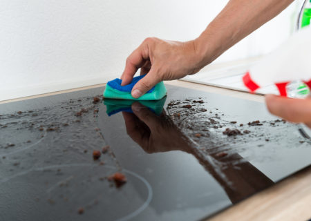 cleaning dirty glass stovetop of food spill
