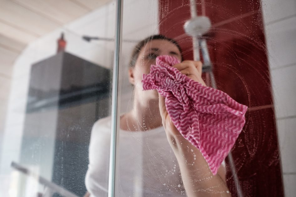 Caucasian tired woman cleaning shower stall with soap