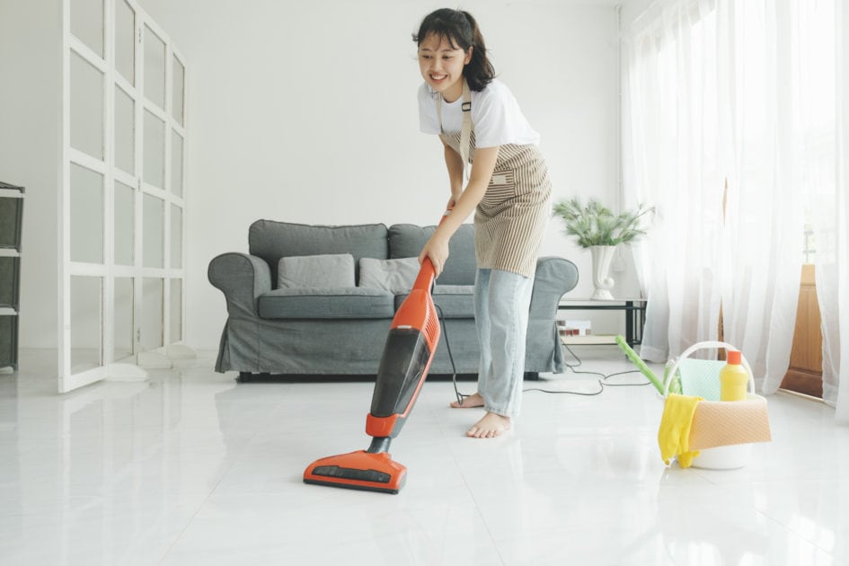 young woman cleaning house with vacuum cleaner