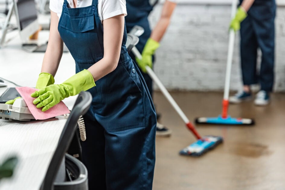 Cleaning professionals scrubbing office surfaces and mopping floors as part of a general cleaning routine